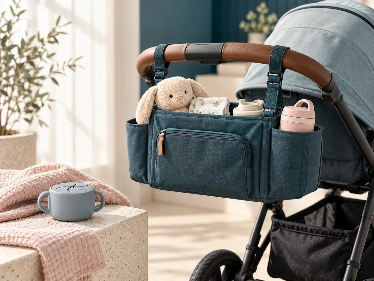 Composición editorial: una bolsa organizadora azul sujeta al manillar de un coche de bebé vacío.