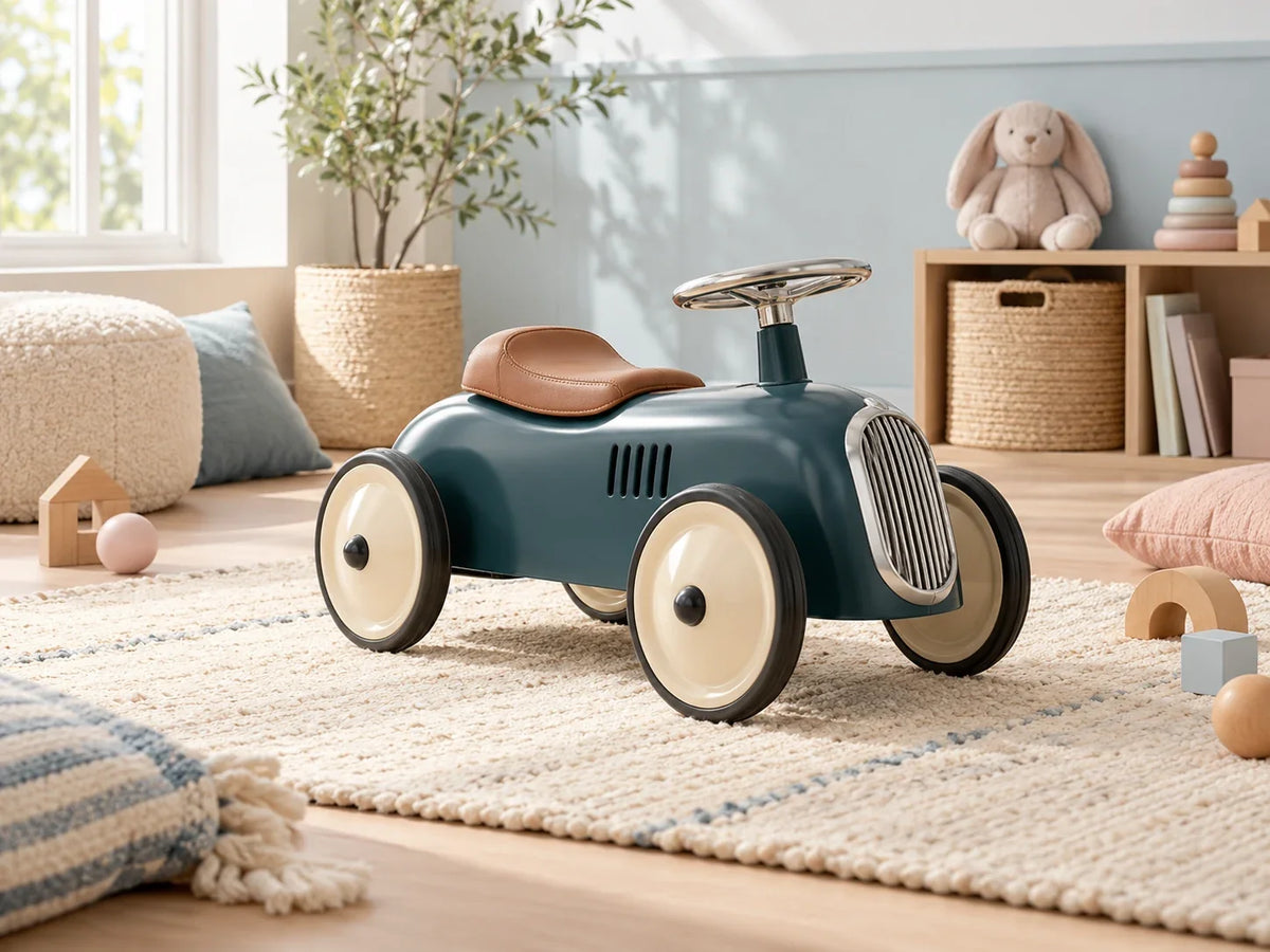 Composición editorial: un vehículo infantil azul para montar, con volante y ruedas claras.